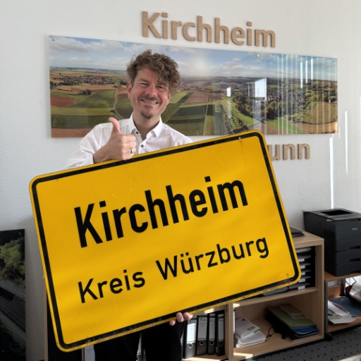 Erster Bürgermeister Christian Stück hält das Ortsschild in die Höhe.
